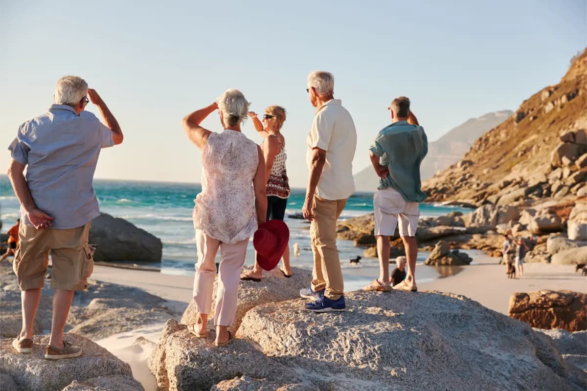 Groupe de seniors profitant d’un voyage organisé en bord de mer, admirant le paysage.